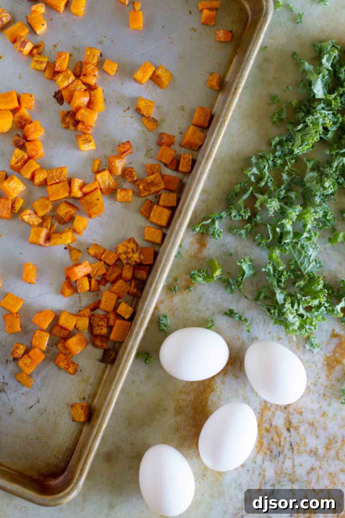 Fresh and colorful ingredients for Butternut Squash Quiche with Kale, prepped and ready. All the fresh ingredients laid out on a kitchen counter, ready for preparing the Butternut Squash Quiche with Kale, including cubed squash, fresh kale, eggs, and cheese.