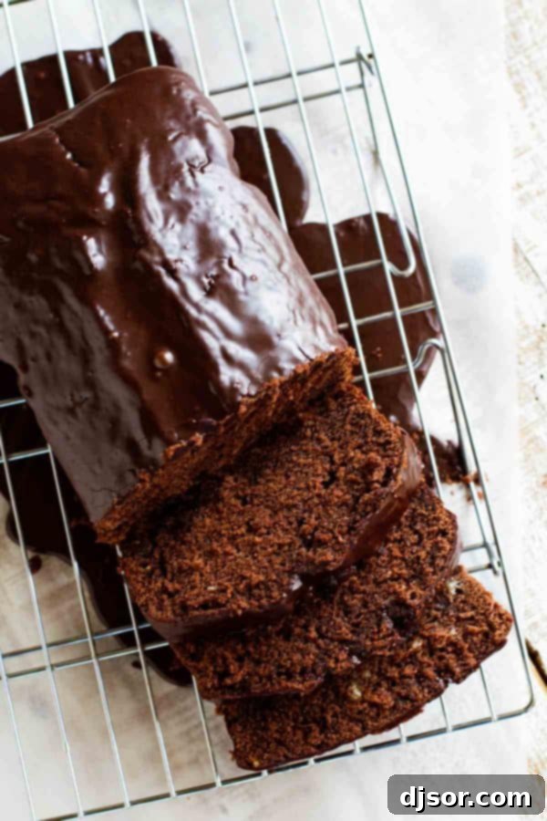 Several slices of rich Chocolate Pound Cake, generously coated with a glossy dark chocolate glaze, arranged on a white plate, highlighting its dense texture and chocolate chips.