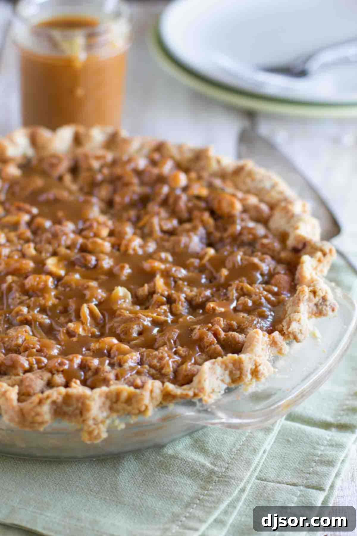 A freshly baked Peanut Butter Fudge Pie, waiting to be drizzled with its signature caramel. Peanut Butter Fudge Pie topped with salted peanut butter caramel, cooling in a pie dish.
