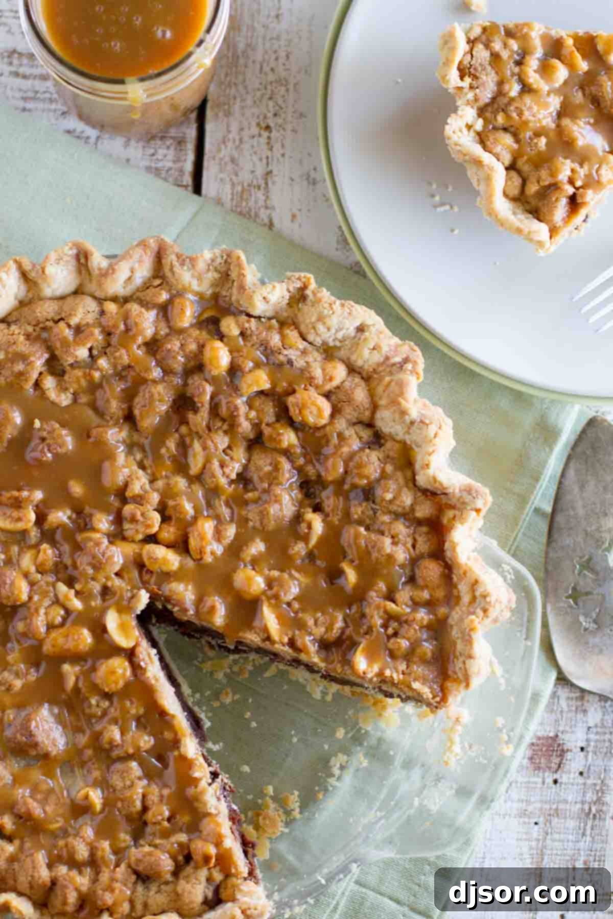 The ultimate indulgence: a perfectly sliced Peanut Butter Fudge Pie, ready to be enjoyed. A full Peanut Butter Fudge Pie with a single perfect slice removed, showcasing its layers and rich caramel topping.