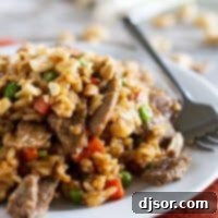 Beef stir fry with rice and vegetables on a plate with a fork.