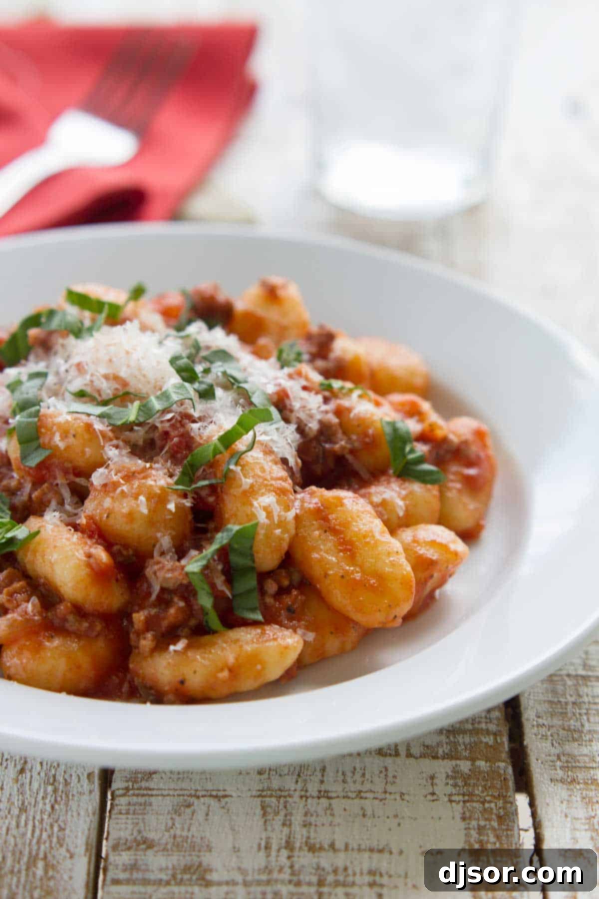 Pillowy Gnocchi with Rich Meat Ragu 2 Easy gnocchi with meat sauce, topped with fresh parmesan and fresh basil in a bowl.