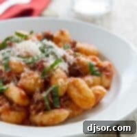 Pillowy Gnocchi with Rich Meat Ragu 5 Easy gnocchi with meat sauce, topped with fresh parmesan and fresh basil in a bowl.