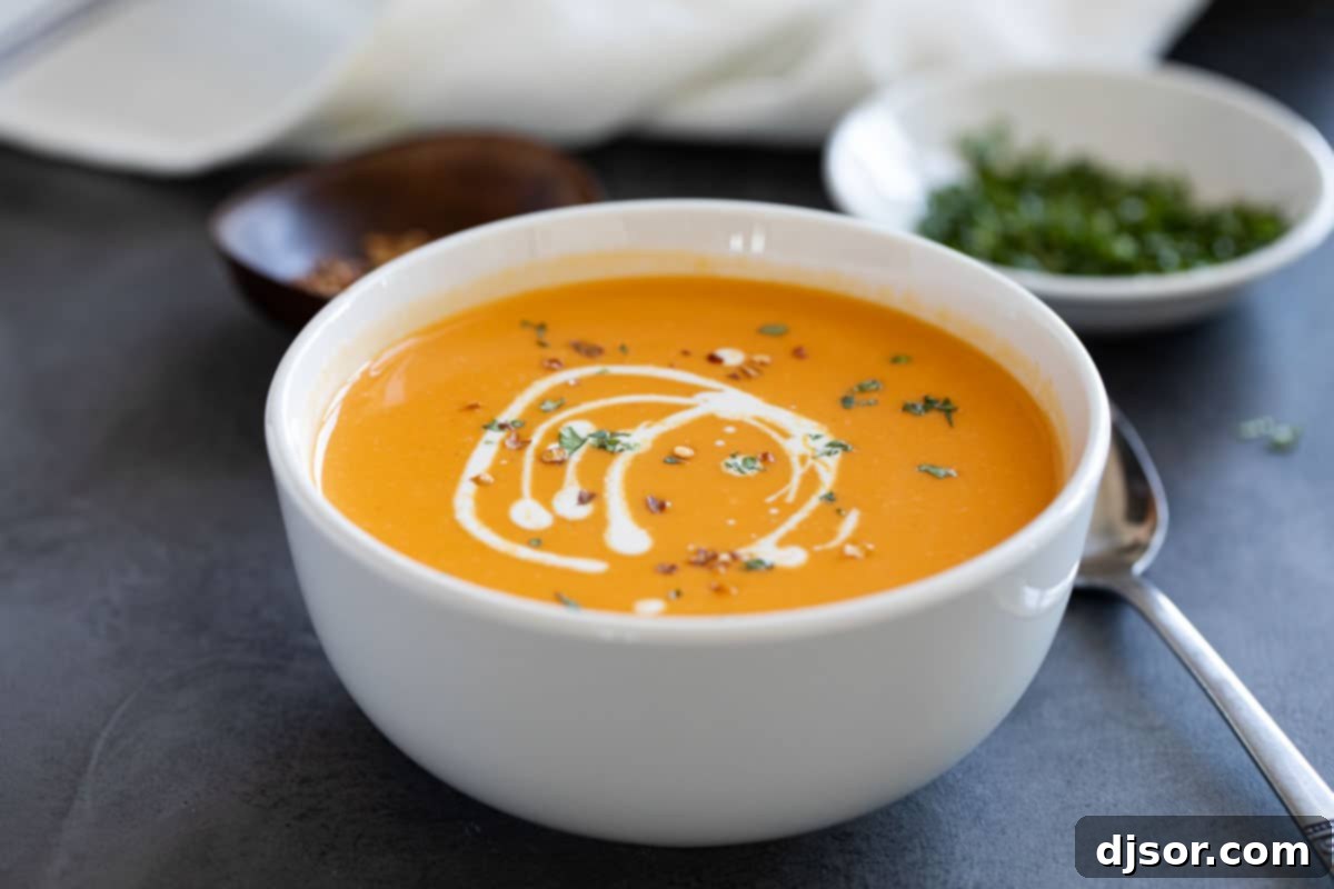 Creamy and delicious, this Sweet Potato Soup is super simple with a hint of curry and nutmeg. It is perfect as a starter, or serve it up with fresh bread for a comforting dinner. Bowl of sweet potato soup topped with red pepper flakes, cream, and parsley.