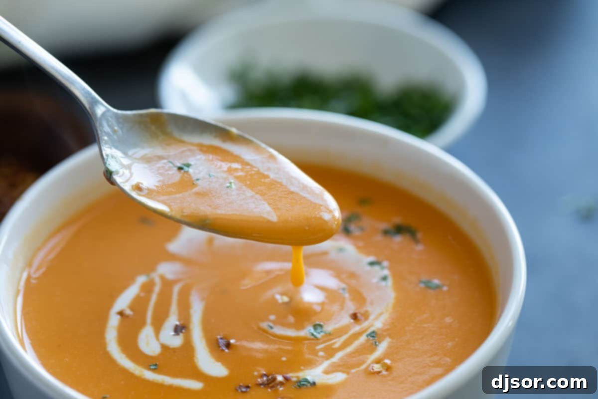 Creamy and delicious, this Sweet Potato Soup is super simple with a hint of curry and nutmeg. It is perfect as a starter, or serve it up with fresh bread for a comforting dinner. Bowl of sweet potato soup with a spoon.