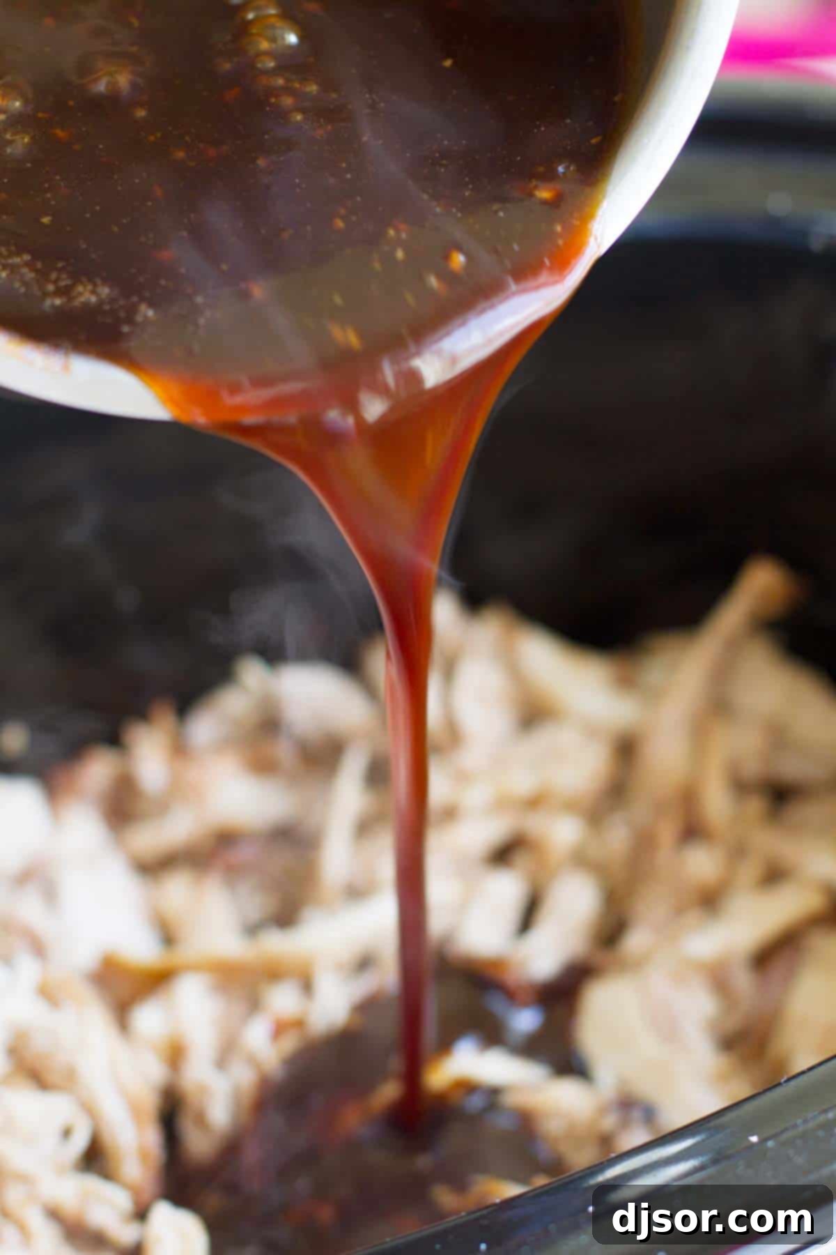 Pouring sauce over slow cooker chicken.