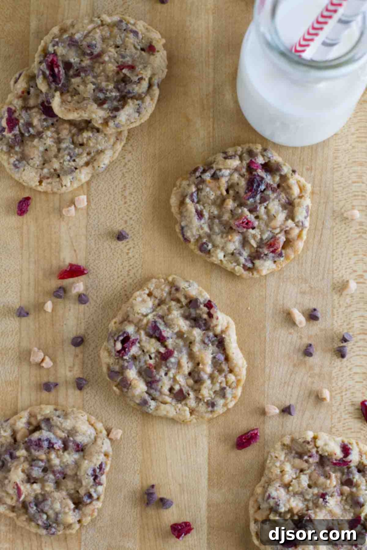 Enjoy these delightful Oatmeal Cranberry Cookies with Chocolate and Toffee, perfectly paired with a glass of cold milk. A cutting board holds several baked Oatmeal Cranberry Cookies with Chocolate and Toffee, accompanied by a glass of refreshing milk.