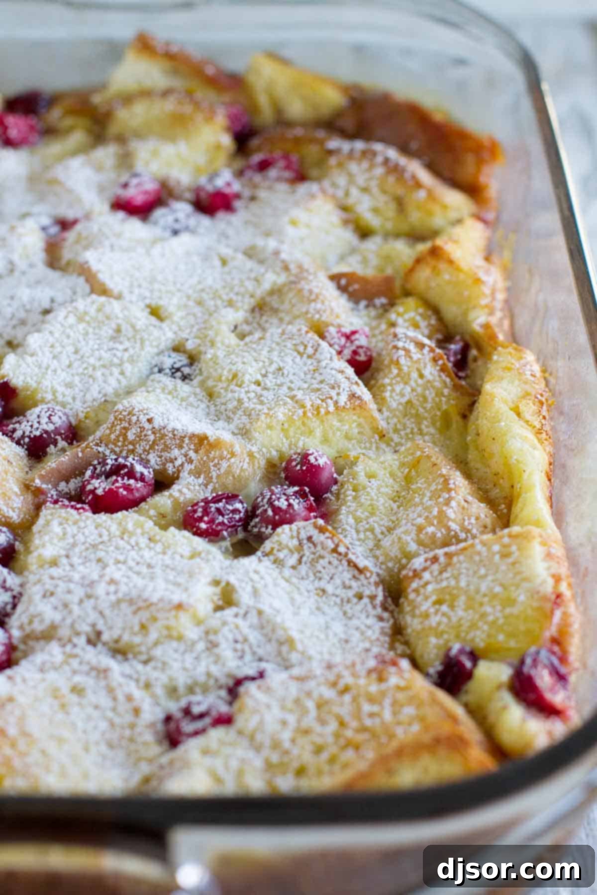 Overnight Cranberry Orange French Toast Bake 3 Cranberry orange baked French toast casserole in a baking dish topped with powdered sugar.