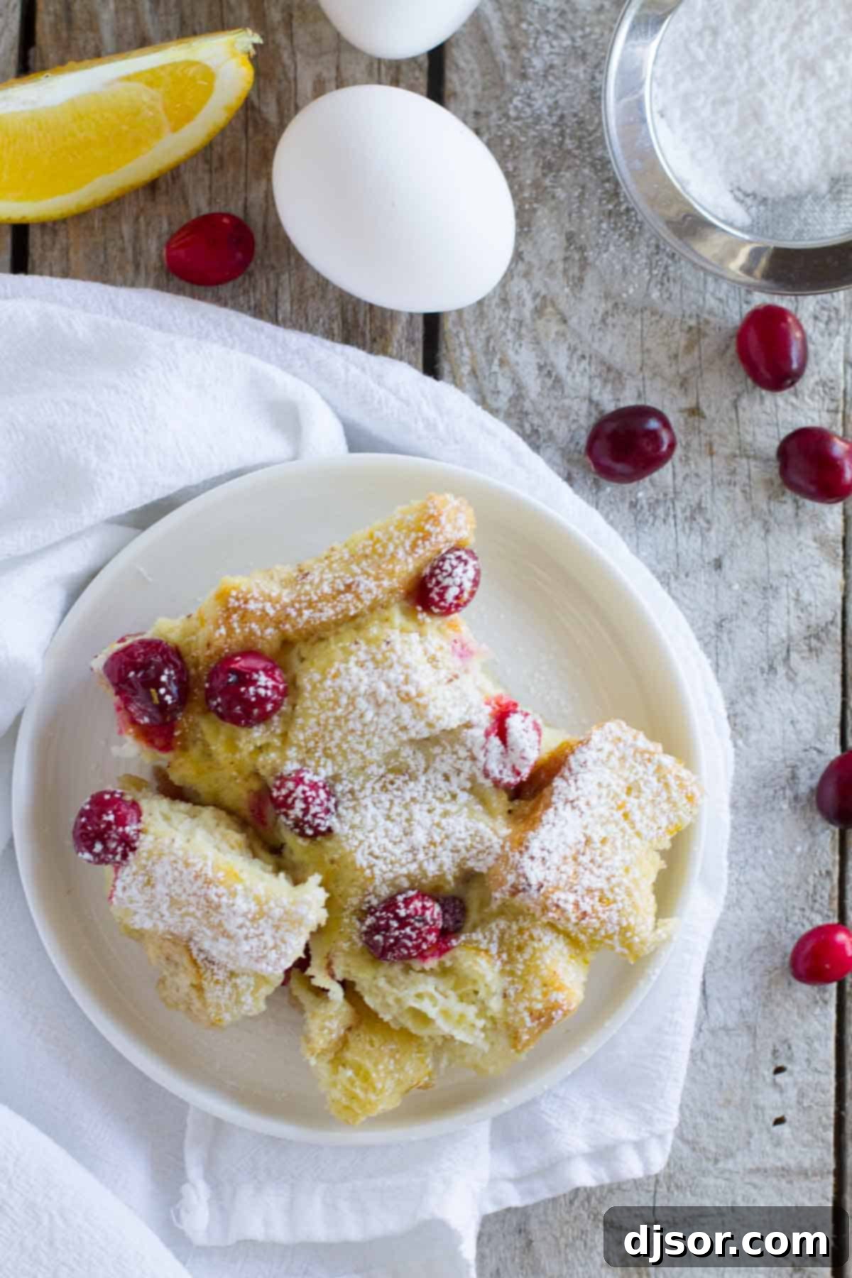 Overnight Cranberry Orange French Toast Bake 4 Serving of Cranberry Orange Baked French Toast Casserole on a small white plate.