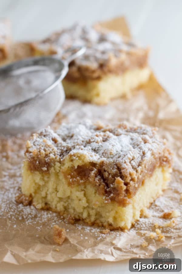 A perfectly baked crumb cake with a thick, golden-brown crumb topping, presented on a rustic wooden surface, highlighting its moist interior.