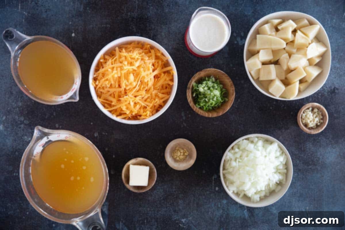 A collection of fresh, high-quality ingredients laid out for making Cheddar Cheese Soup, including whole onions, russet potatoes, garlic cloves, a block of sharp cheddar cheese, and fresh chives, ready for preparation.
