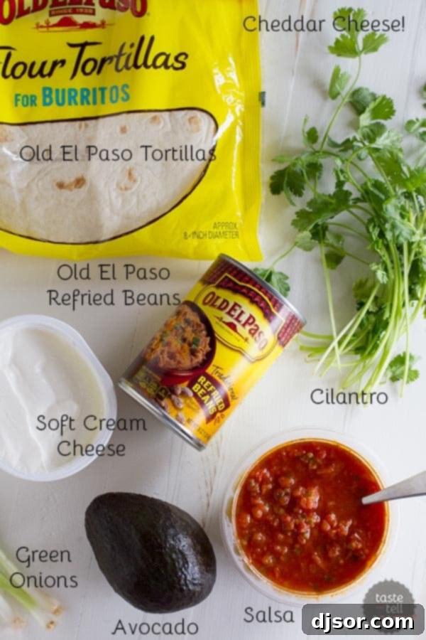 A colorful array of ingredients including refried beans, cheese, tortillas, avocado, salsa, green onions, and cilantro, ready for making vegetarian wraps.