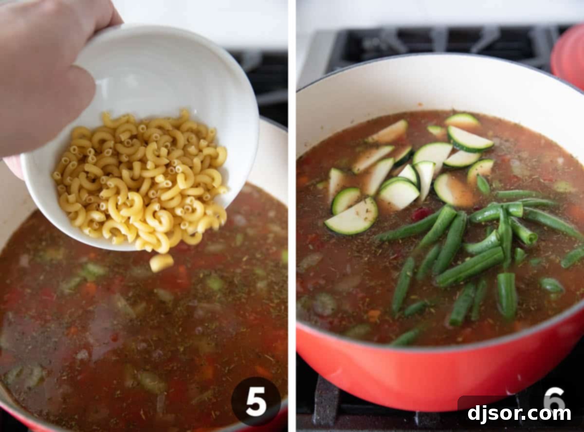 Short-cut pasta, kidney beans, sliced zucchini, and fresh green beans are being added to the simmering Minestrone Soup in a pot, completing the hearty vegetable mix.