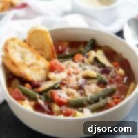 A comforting bowl of Minestrone Soup, ready to be enjoyed with a side of toasted bread.