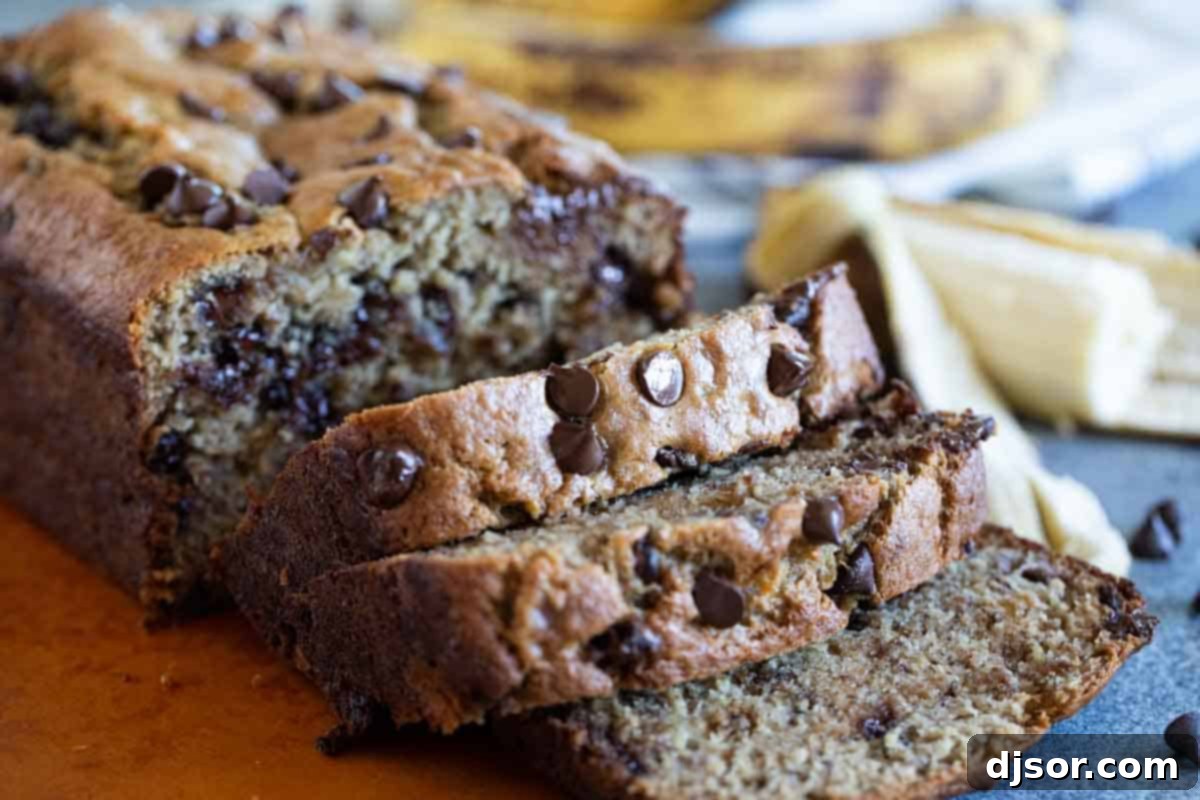Fit for a king, this Peanut Butter Banana Bread with Chocolate Chips is a fun take on Elvis’ favorite flavor combination - peanut butter and bananas. A perfectly sliced loaf of Peanut Butter Banana Bread with Chocolate Chips resting on a wooden cutting board, showcasing its moist texture and rich chocolatey peanut butter swirls.