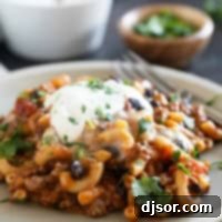 Serving of Chili Mac on a plate, topped with sour cream.