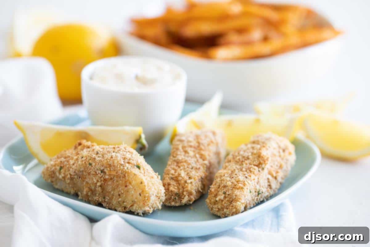 Homemade crispy fish sticks served on a blue plate with fresh lemon wedges, ready to eat.