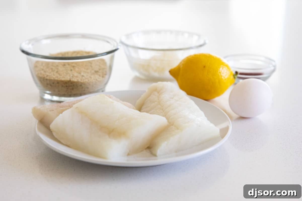 A selection of fresh ingredients laid out on a wooden cutting board for making homemade fish sticks.