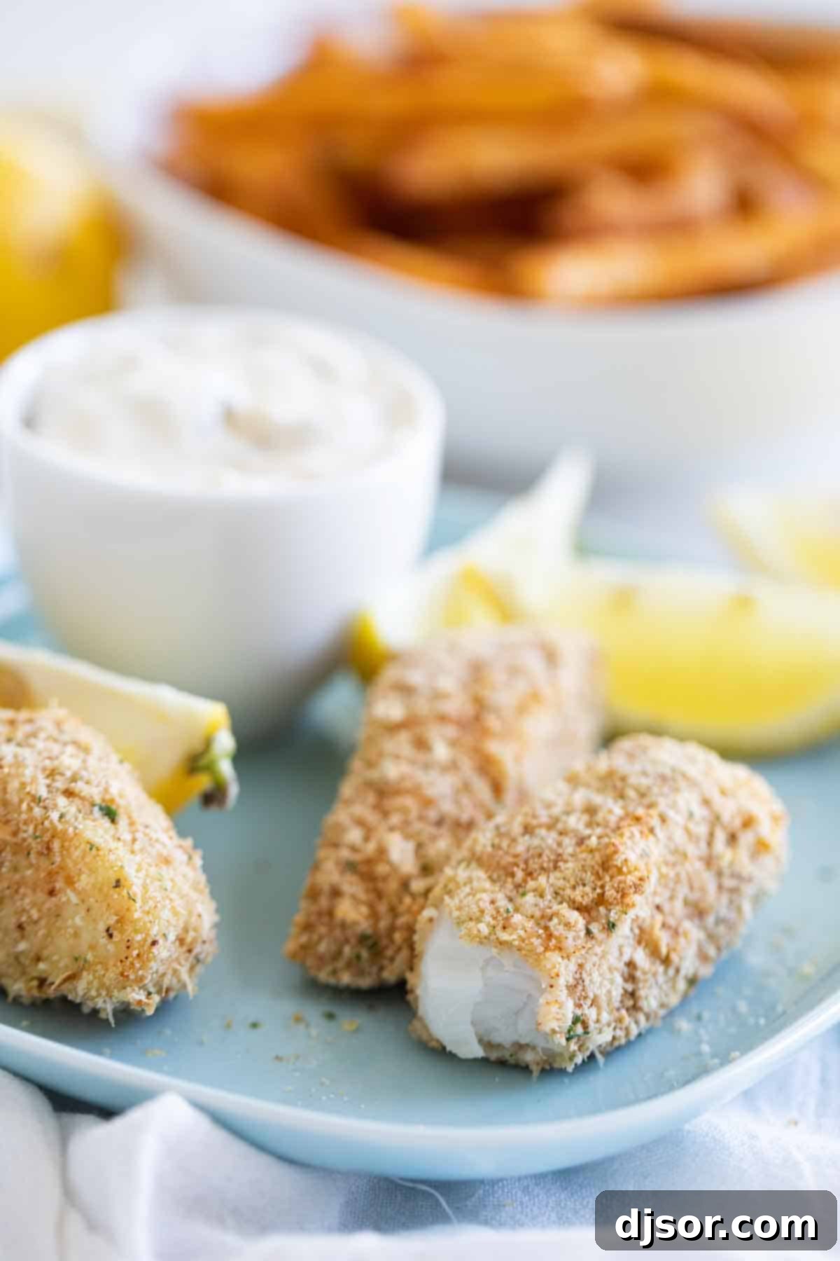 Close-up view of a baked fish stick cut open, showing the flaky white fish texture and crispy golden breading.