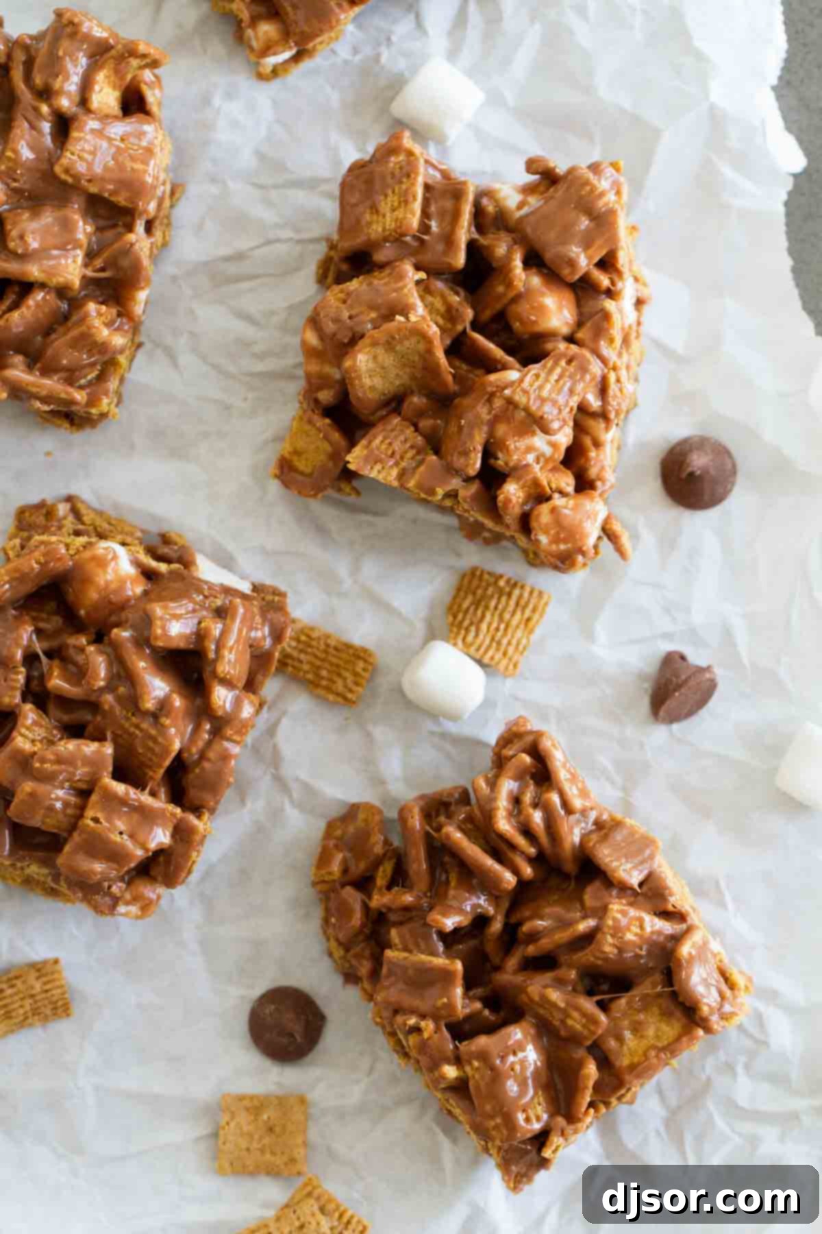 Homemade Indoor S'mores Bars: A Deliciously Simple Dessert Close-up overhead view of freshly made Indoor S'mores cereal bars cooling on parchment paper, showing the melty chocolate and marshmallow pieces.