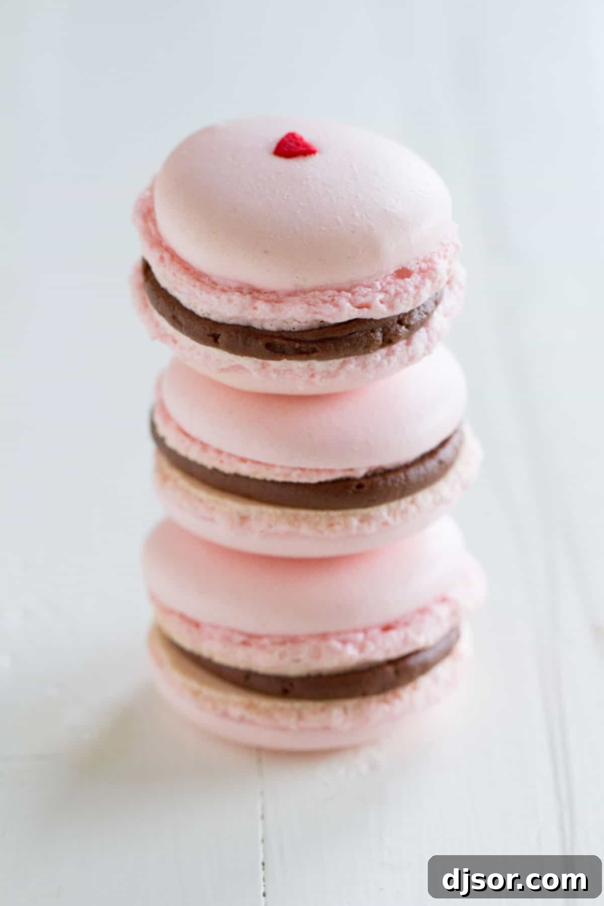 Parisian Chocolate Cherry Macarons 2 Three decadent Chocolate Cherry French Macarons stacked elegantly, showcasing their rich color and delicate feet.