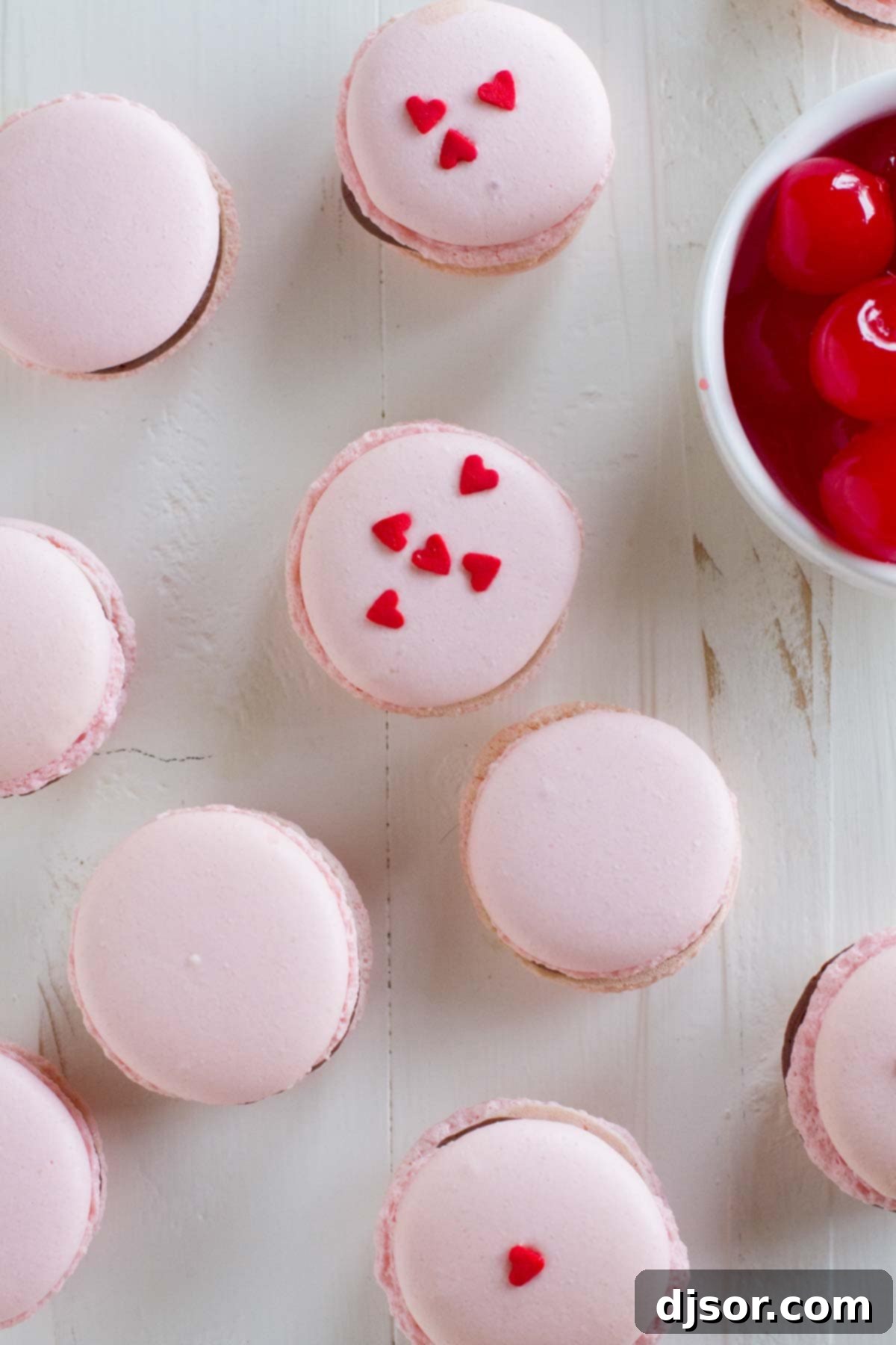 Parisian Chocolate Cherry Macarons 4 A delightful arrangement of Chocolate Cherry French Macarons, some adorned with festive heart sprinkles, perfect for a special occasion.