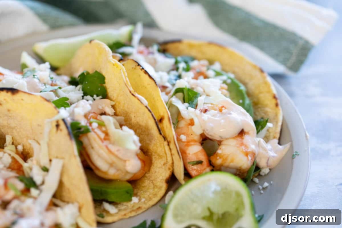 Plate with shrimp tacos topped with queso fresco, cabbage, and homemade chipotle lime crema.