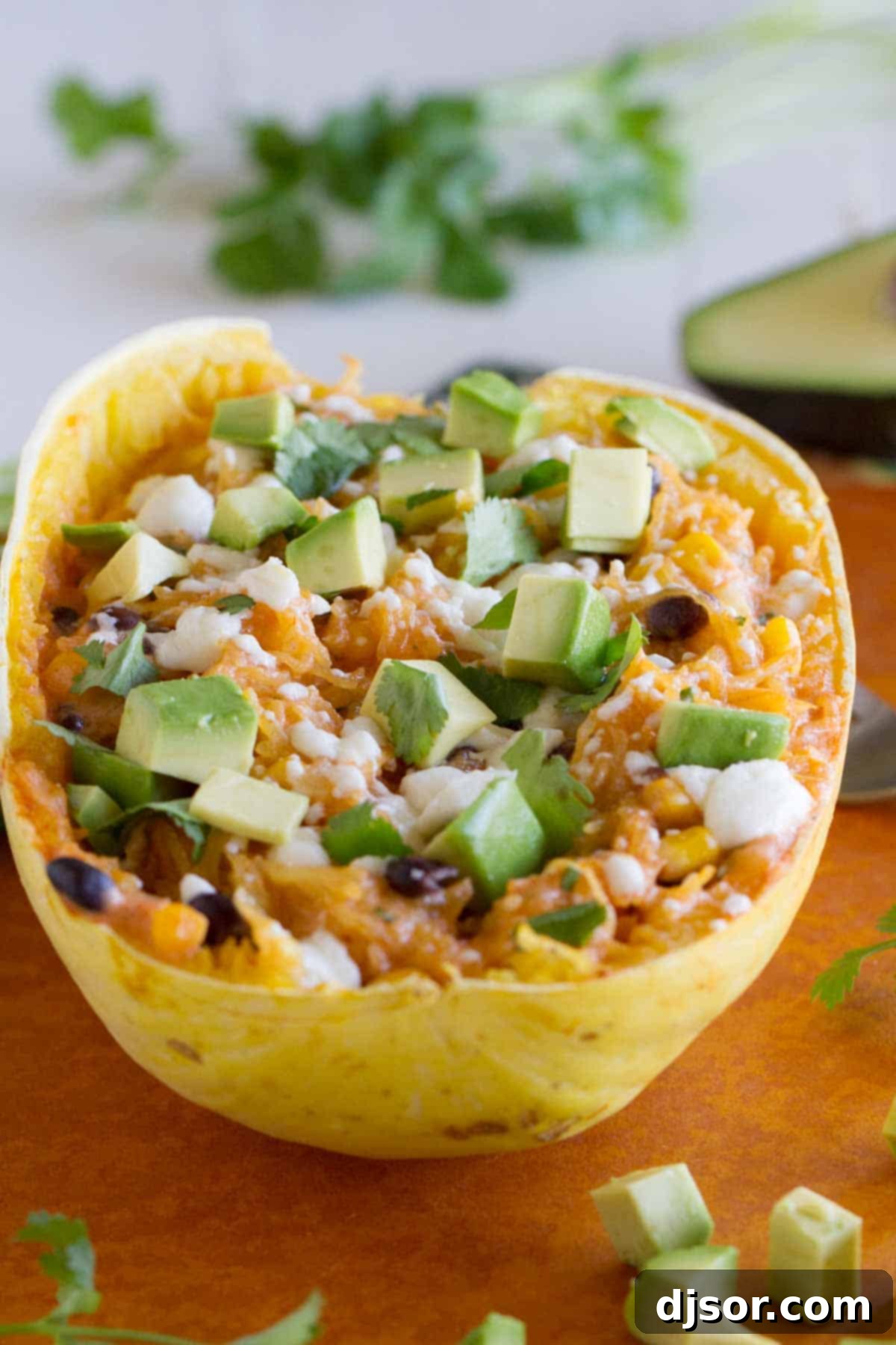 A perfectly cooked half of spaghetti squash, generously filled with a robust mixture of black beans, corn, rich enchilada sauce, and melted cheese.