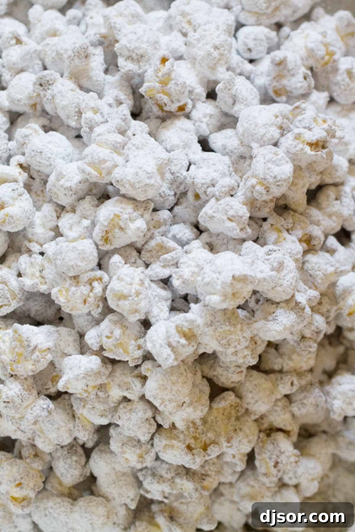 Freshly coated popcorn, perfectly dusted with powdered sugar, ready to be poured into a bowl.