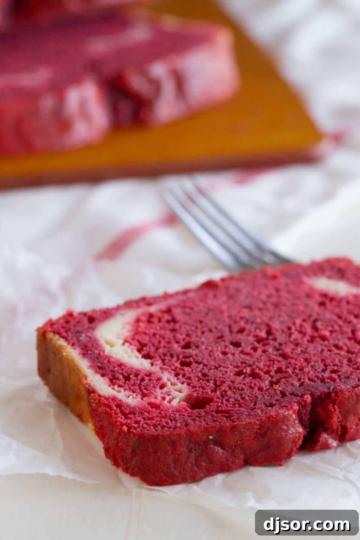 Close-up slice of red velvet quick bread with cream cheese filling, showing the beautiful swirl and texture.