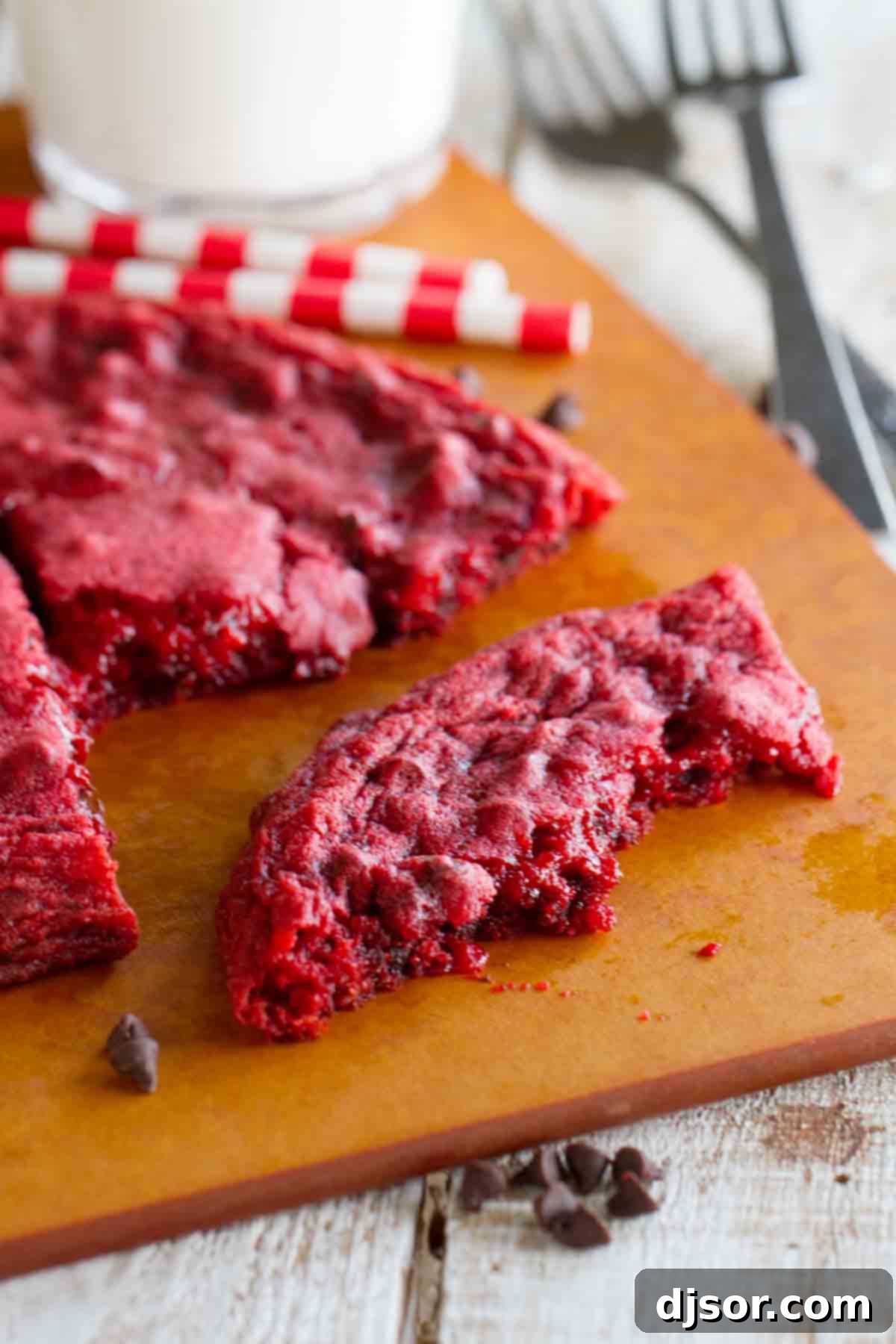 XL Red Velvet Cookie broken apart to show its tender, gooey interior texture and melted chocolate chips.