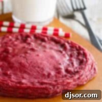 XL Red Velvet Cookie on a cutting board with milk behind