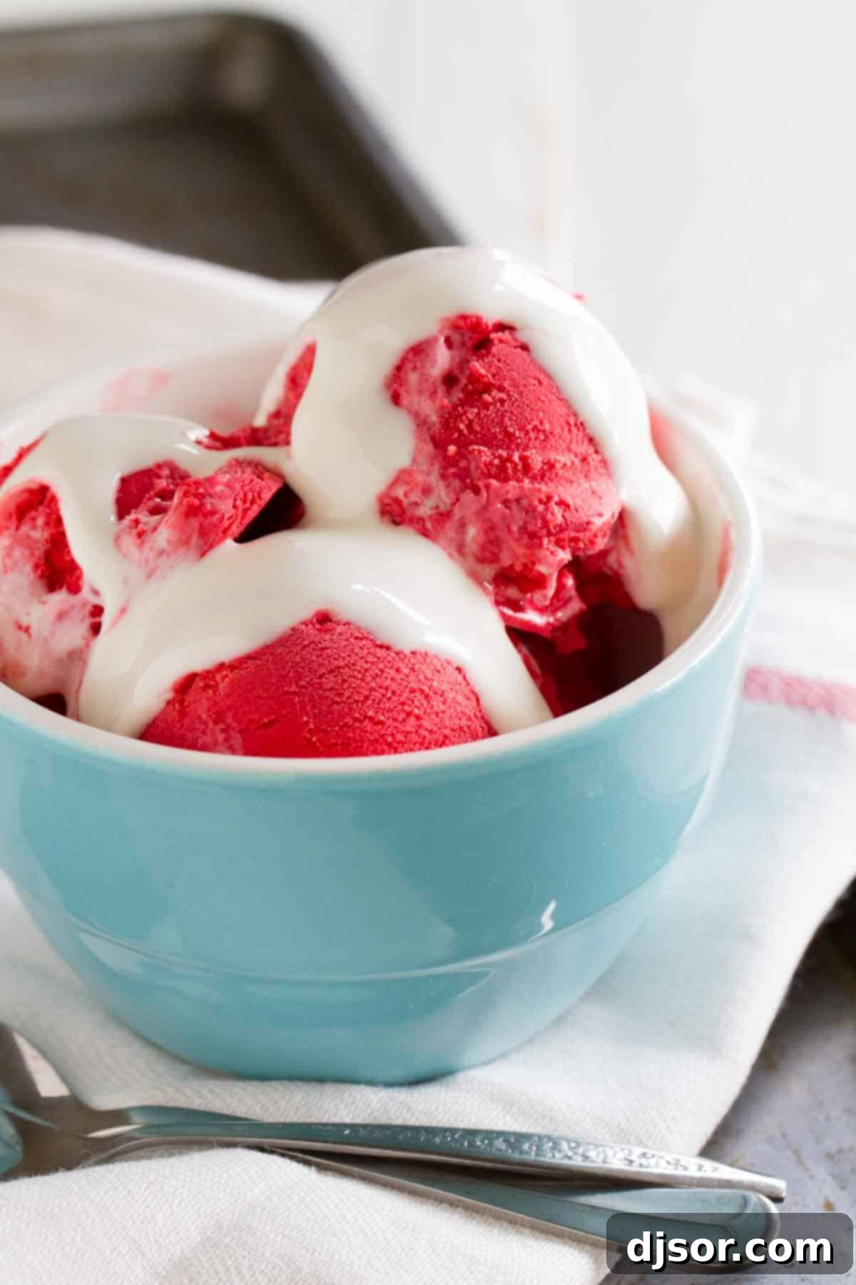 Red velvet ice cream in a bowl, generously topped with a dollop of marshmallow creme and a small red velvet cake bite.