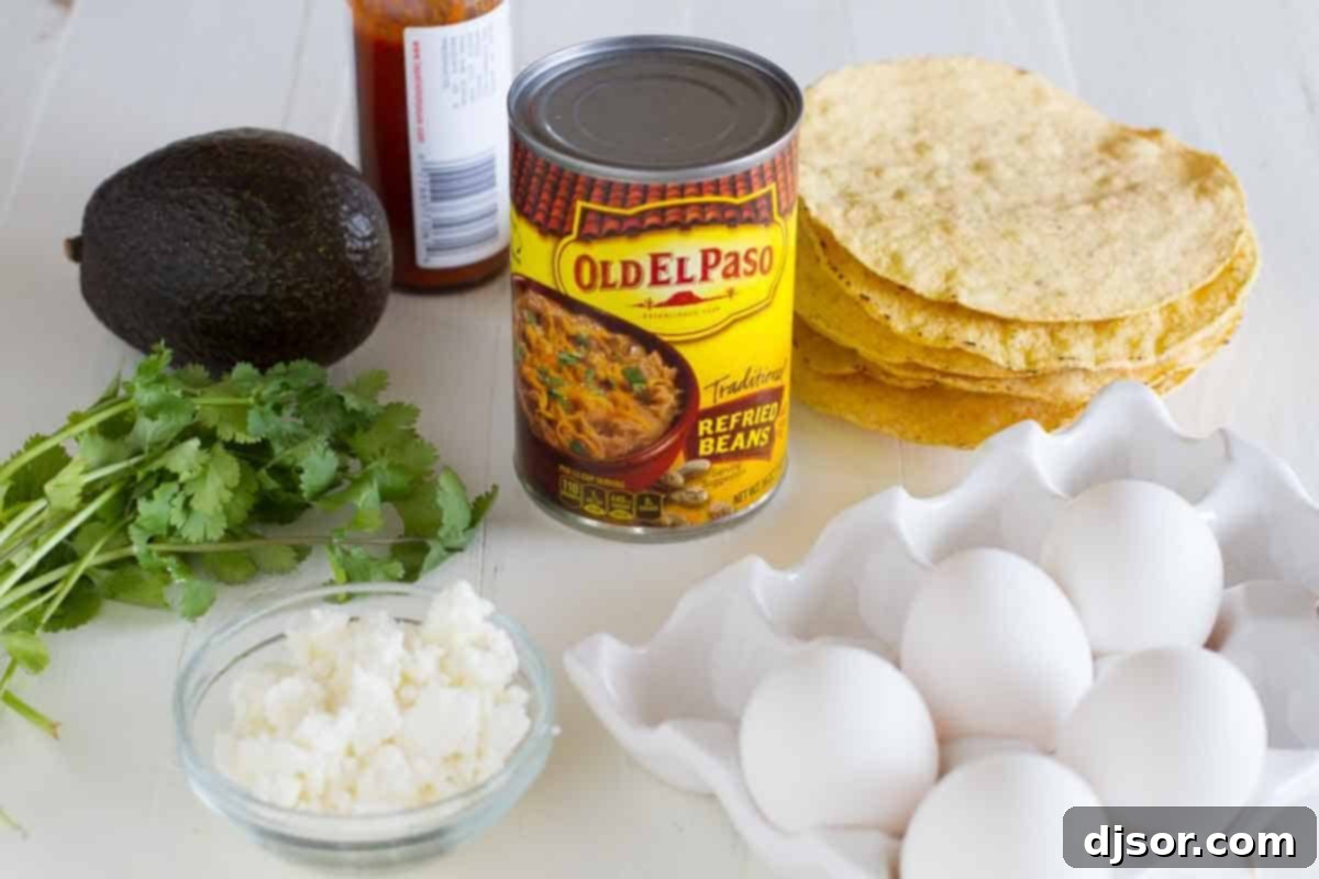 All the essential ingredients neatly laid out for making delicious breakfast tostadas: tostada shells, a can of refried beans, fresh avocado, eggs, crumbled queso fresco, cilantro, and a bottle of hot sauce.