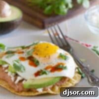 Breakfast tostada on a plate with a fork, showing a perfect sunny-side-up egg