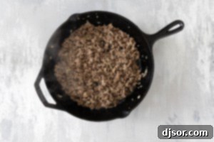 Ground beef and onions cooked in a cast iron skillet.