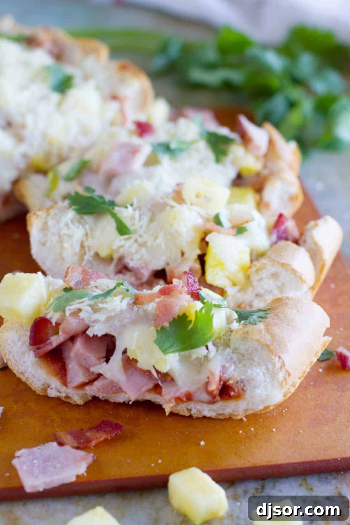 Tropical French Bread Pizza 2 Crispy French Bread Hawaiian Pizza, garnished with fresh cilantro and loaded with ham, bacon, and pineapple.