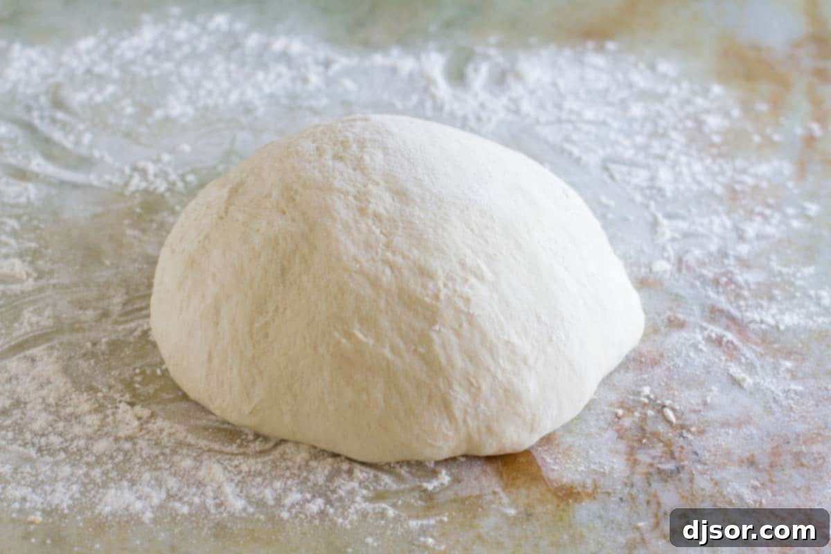 A single, perfectly rounded ball of smooth pizza dough, ready to be divided.