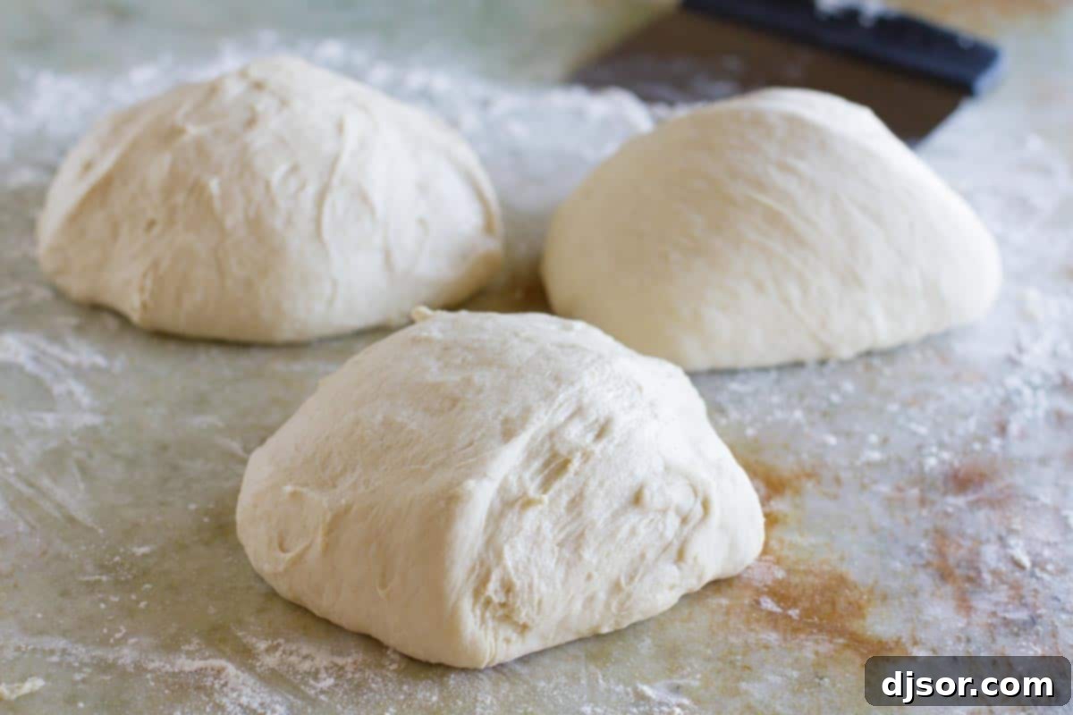 Three perfectly portioned balls of pizza dough, lightly dusted with flour, waiting to be rolled out.