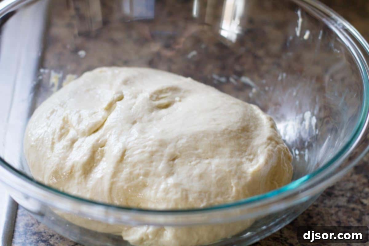 Sticky pizza dough carefully scraped into a large, greased bowl, ready for its first rise.