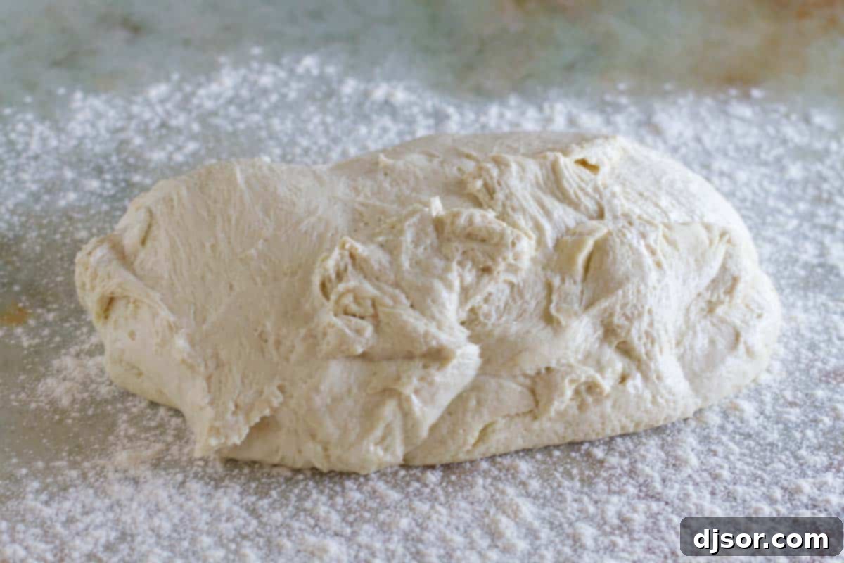 Lightly punched-down pizza dough being turned out onto a well-floured work surface, ready for shaping.
