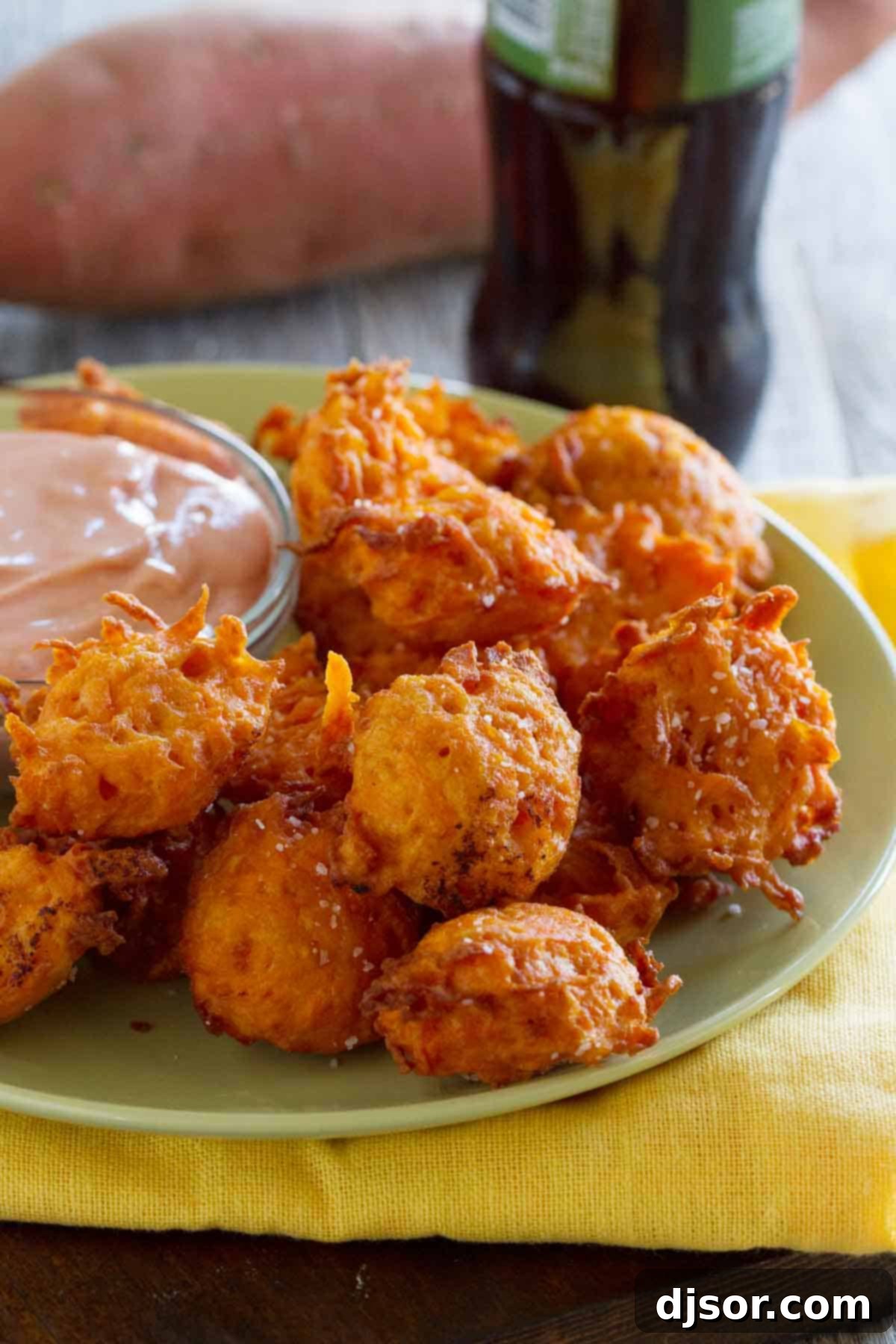 Golden Sweet Potato Tots with Velvety Ketchup 2 Golden brown Sweet Potato Tots piled high on a white plate, with a small ceramic bowl of creamy ketchup nestled beside them, ready for dipping.
