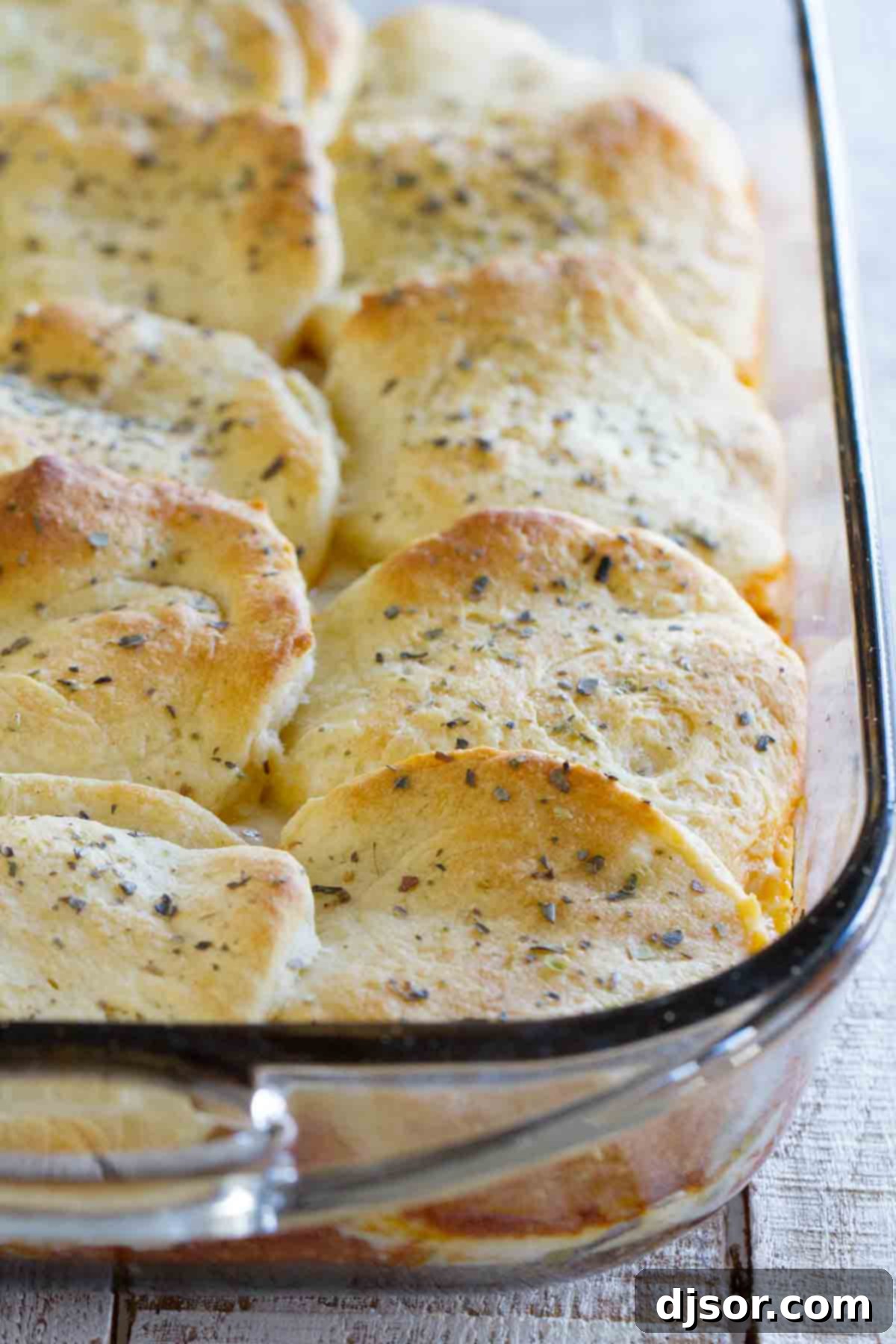 A close-up view of the Italian Ground Beef Casserole with Biscuit Topping, fresh from the oven, showing its golden-brown biscuit crust and bubbling cheesy interior.