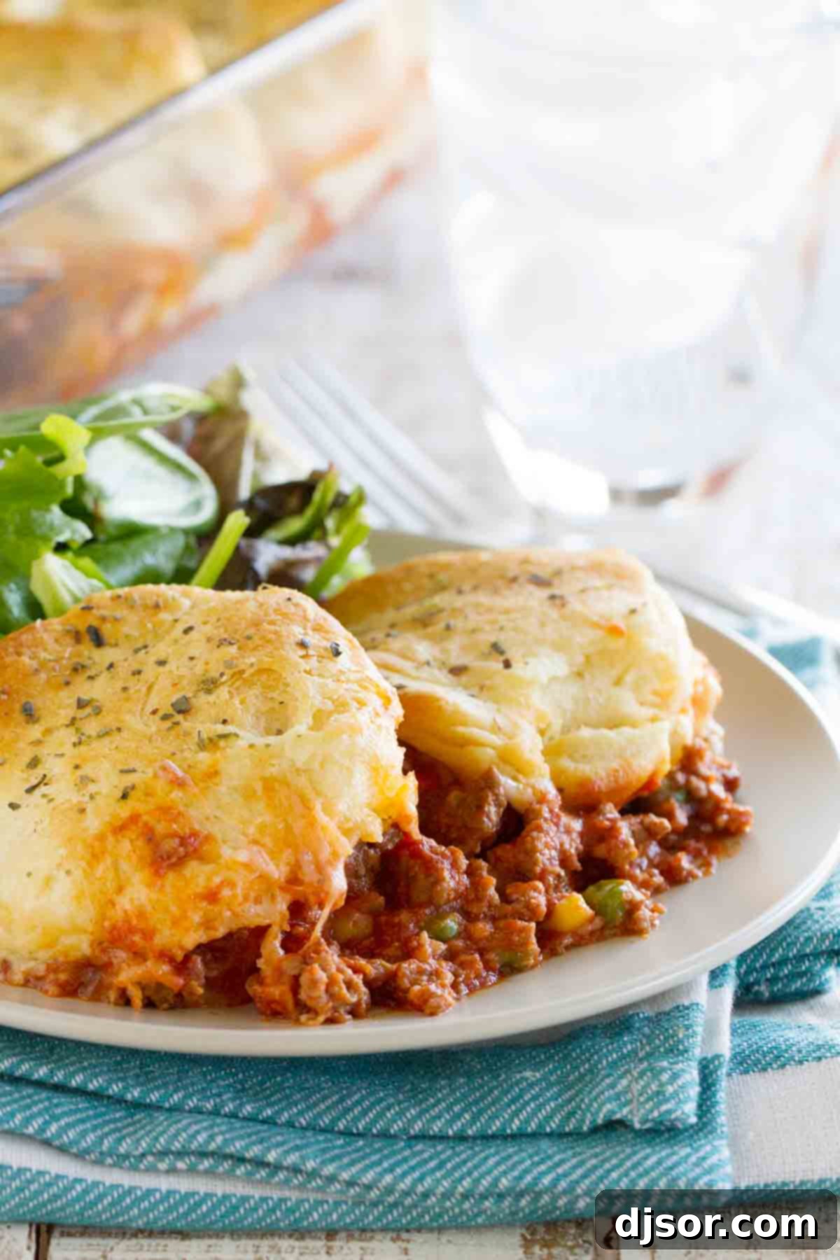 A plate featuring a generous serving of Italian Ground Beef Casserole, showcasing its flaky biscuit topping, melted cheese, and hearty ground beef layers.