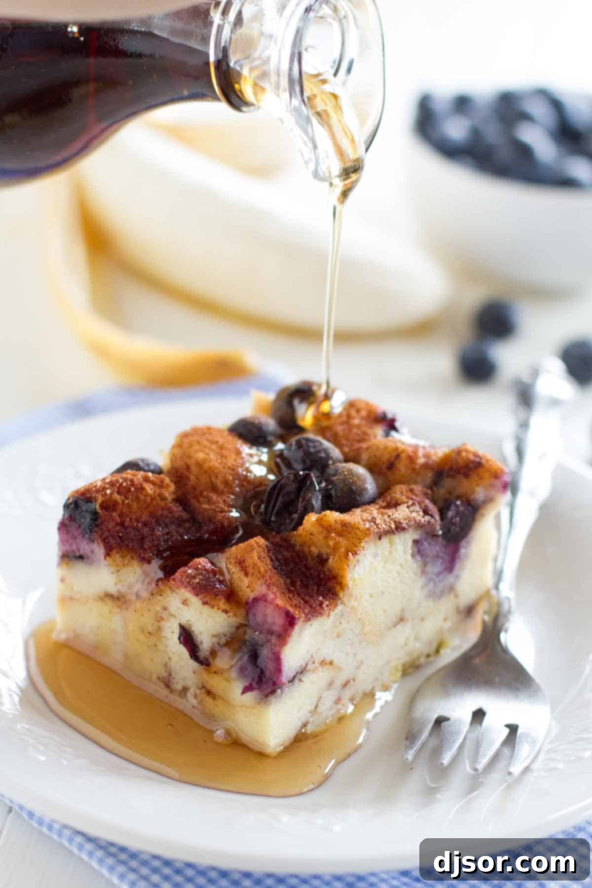 Baked Blueberry Banana French Toast 4 pouring syrup over a slice of blueberry banana french toast bake
