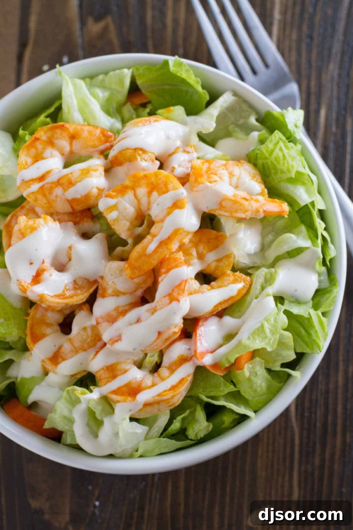 Close-up of Buffalo Ranch Shrimp Salad with crisp lettuce, bright orange buffalo shrimp, and a drizzle of creamy ranch dressing.