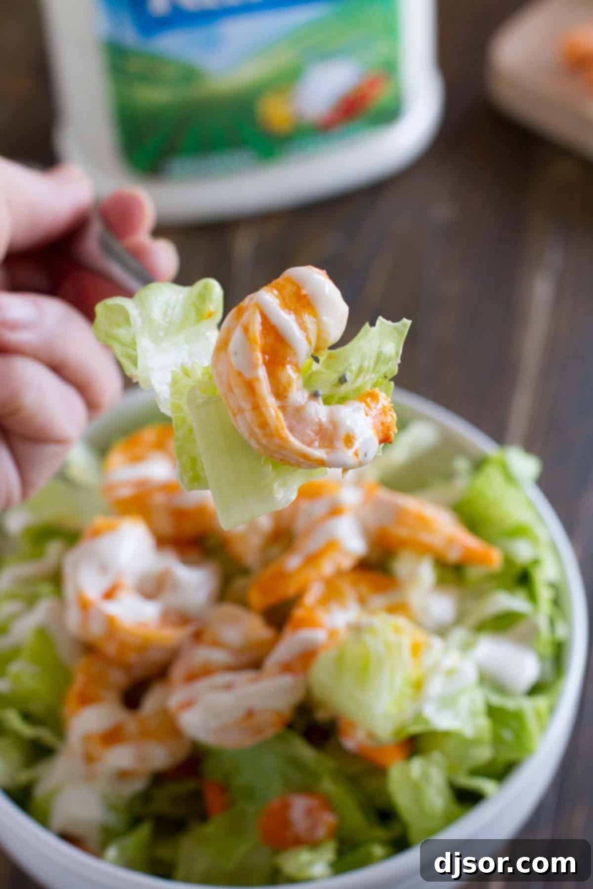 A forkful of Buffalo Ranch Shrimp Salad, showcasing a piece of shrimp, lettuce, and carrot, ready to be eaten.