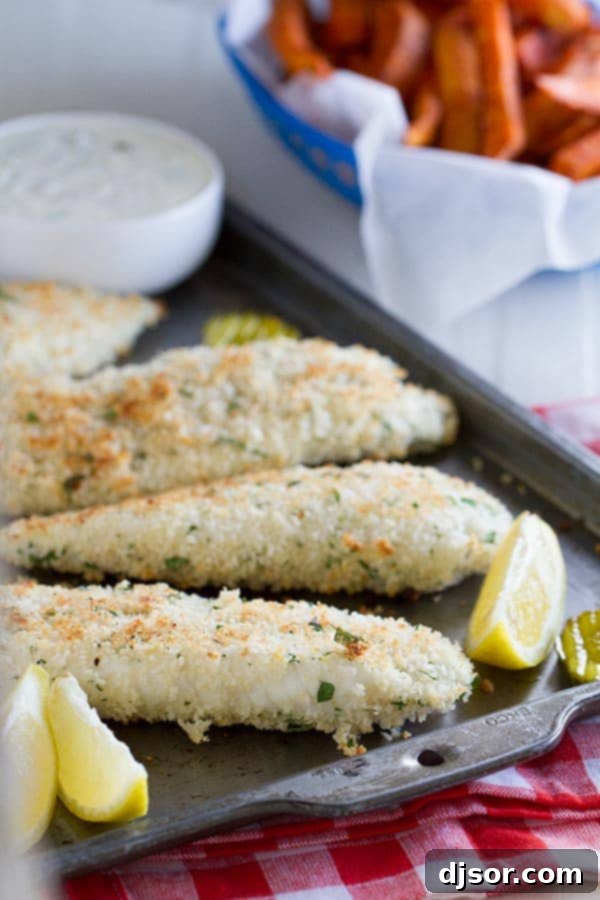 Crispy Panko crusted tilapia fillets on a baking sheet, garnished with fresh lemon slices, ready for serving.