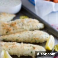Panko crusted tilapia on a baking sheet with lemons.