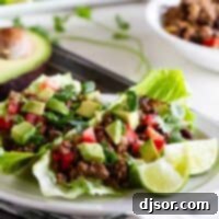 Two taco lettuce wraps on a plate, topped with tomatoes, avocado, and lime juice.